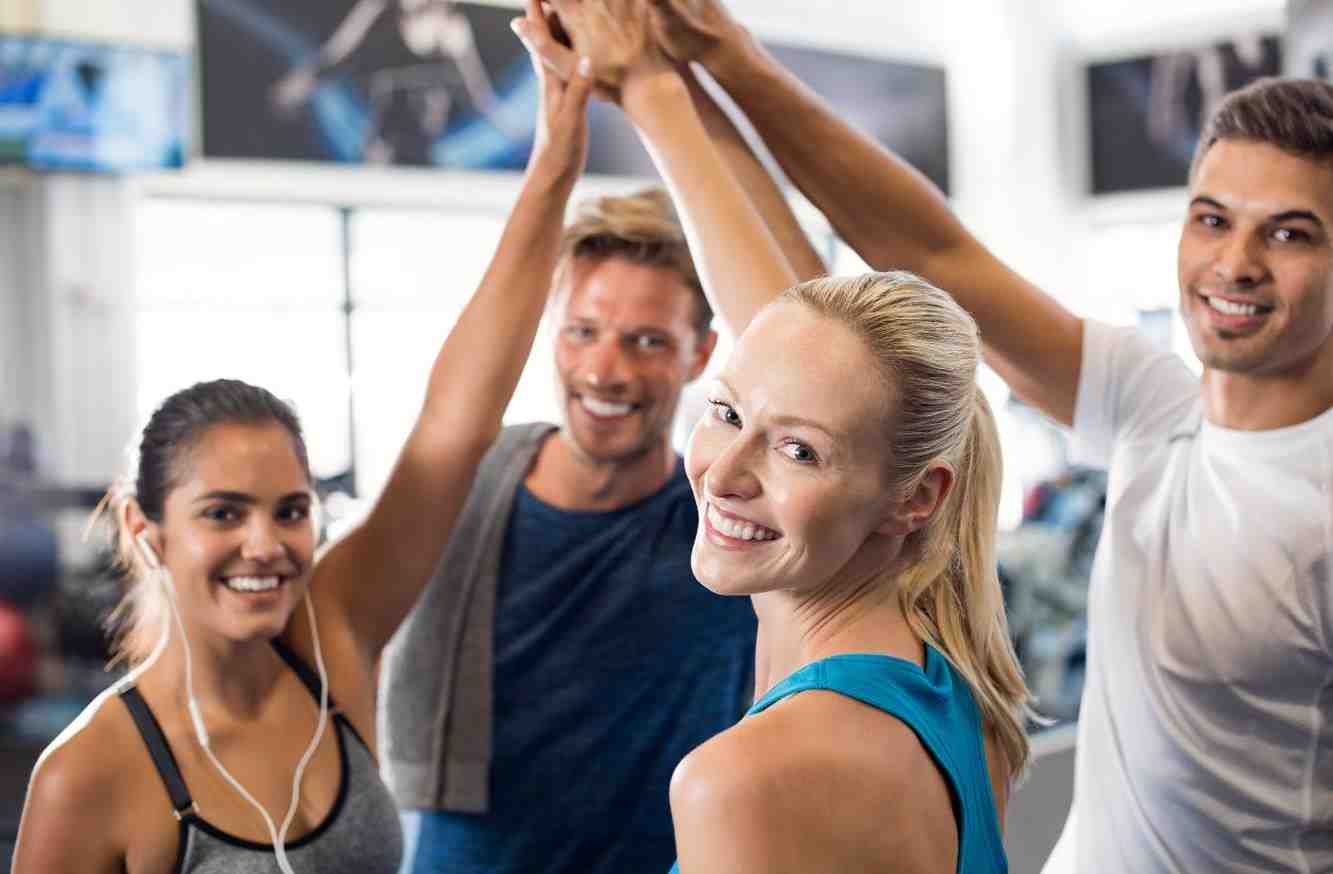 Group of four people celebrating their progress after an intense HIIT workout, showcasing teamwork and fitness achievement.
