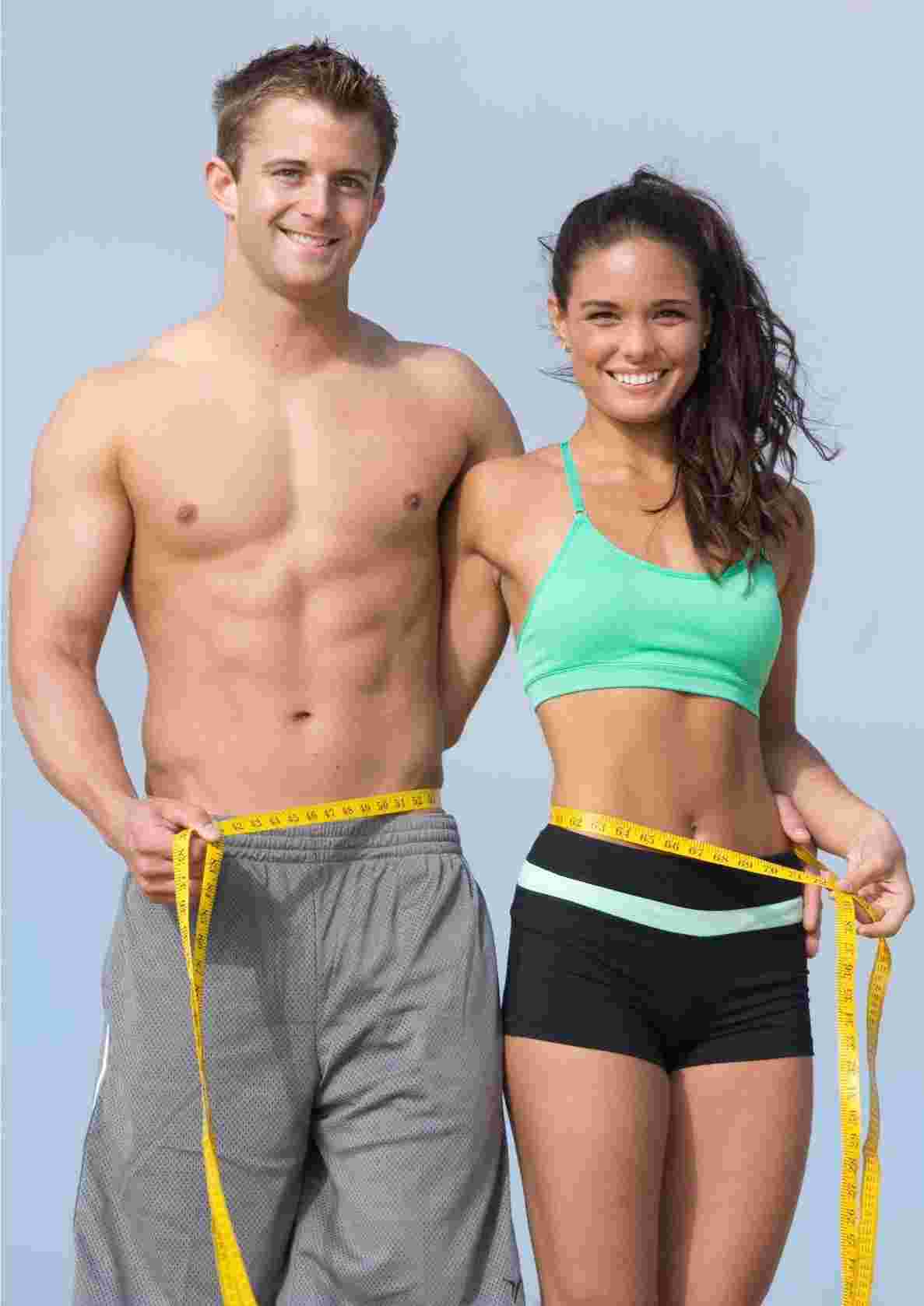 Two people are standing side by side, holding a yellow measuring tape around their waists. They are tracking progress and measuring success in their HIIT weight loss journey.