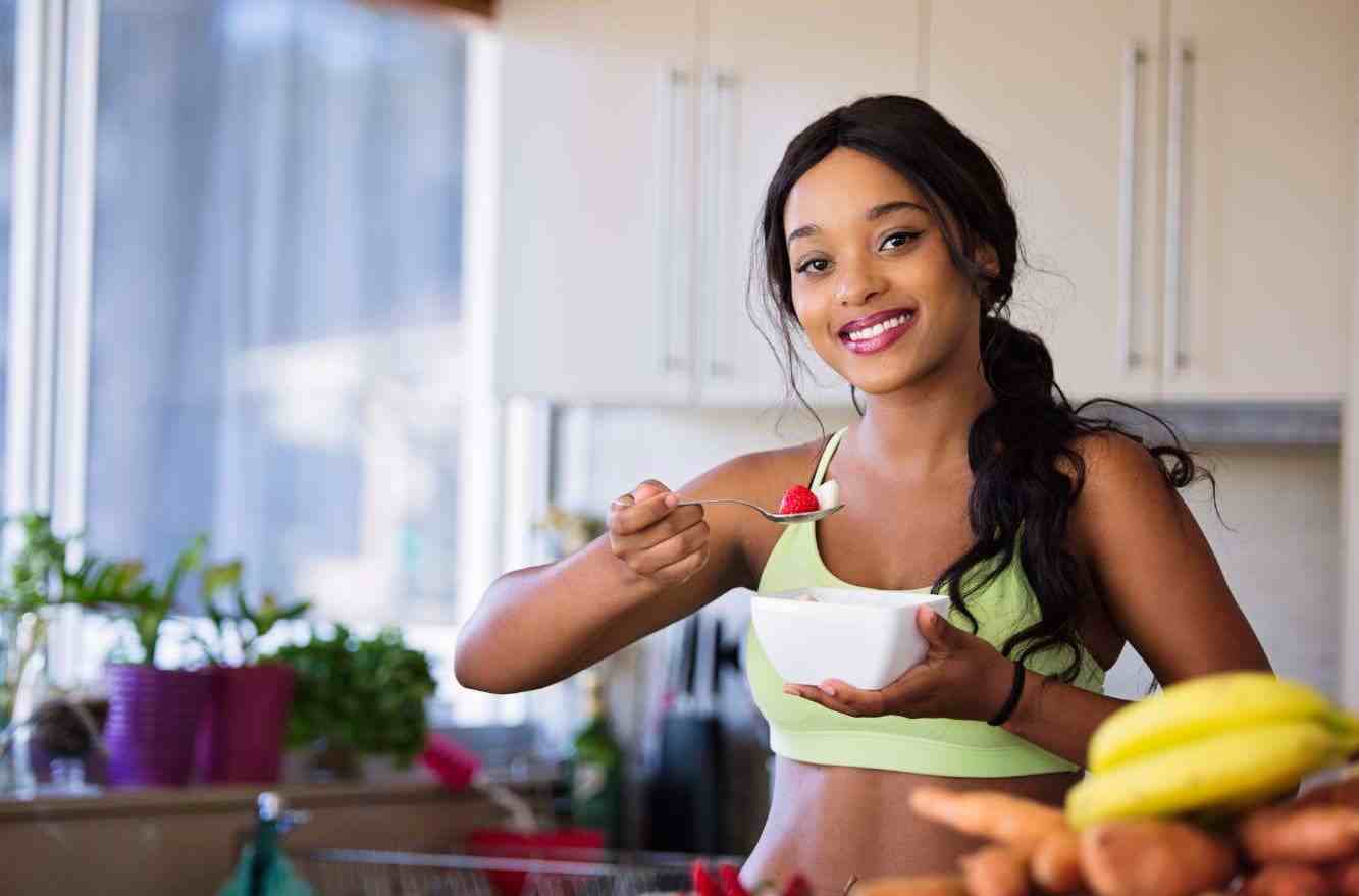 Person enjoying a healthy post-workout snack in the kitchen after a HIIT session, emphasizing the role of nutrition in weight loss.