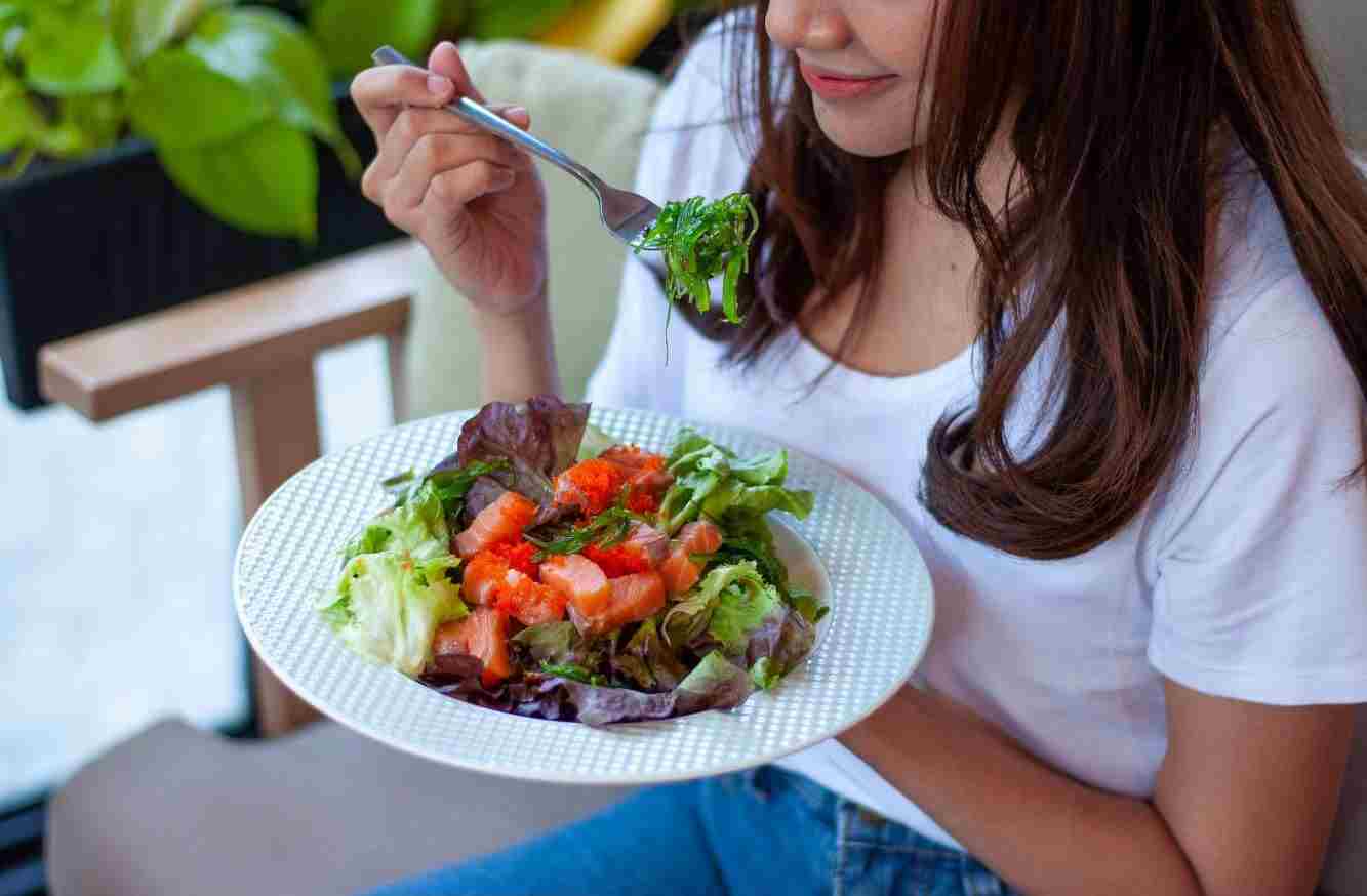A woman enjoying a healthy salad Before a HIIT workout.