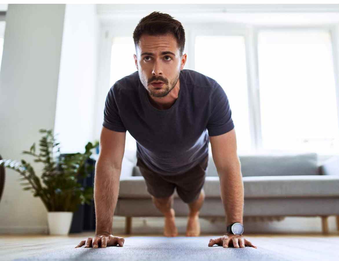 Individual performing push-ups in a cozy living room with natural light, emphasizing the ease of incorporating HIIT workouts at home.