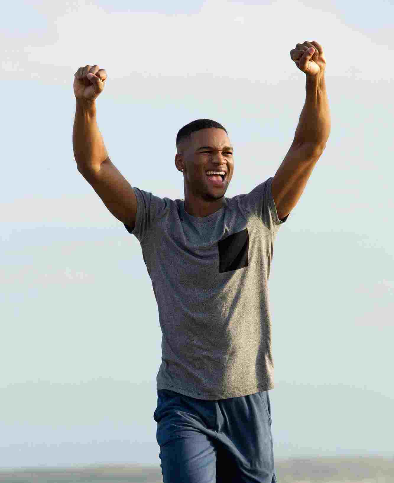 Athlete with arms raised in victory, highlighting the joy of success after an intense HIIT training session in an open-air setting.